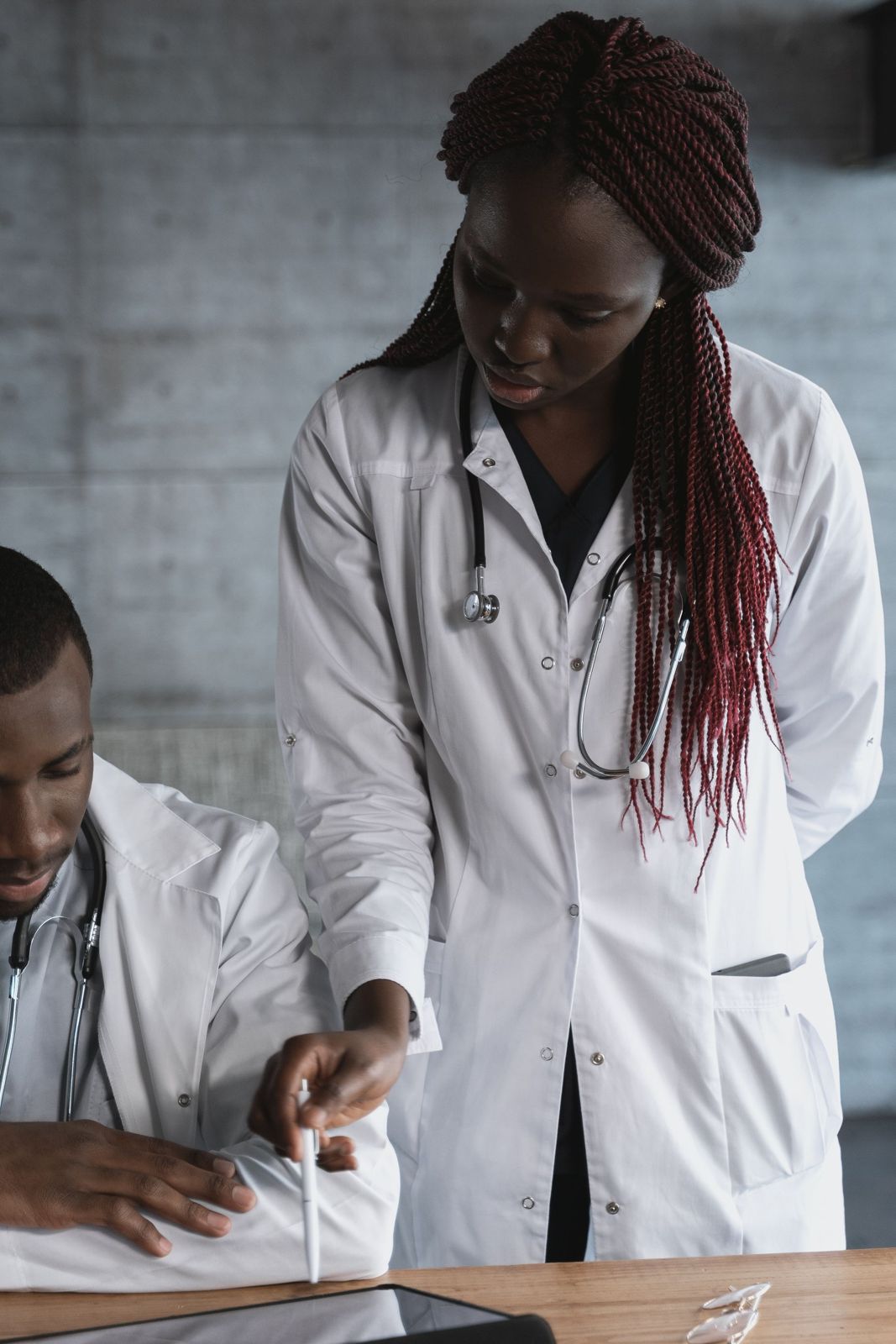 Two Black doctors, a man and a woman, reviewing a tablet together in a clinic